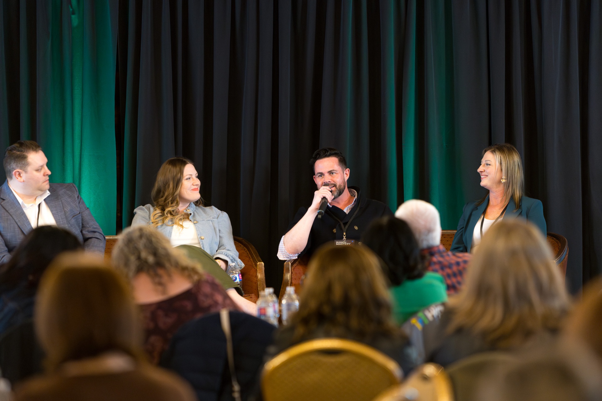 Paul on a panel with a microphone, speaking to a room